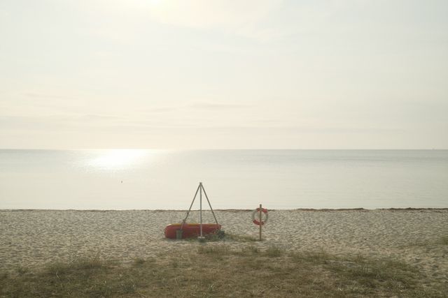a photograph of a man standing on a beach next to a red boat