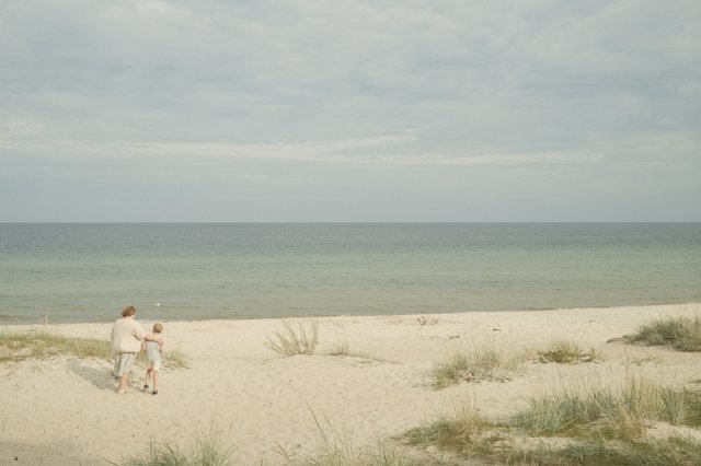 a photograph of a man and a woman walking on a beach