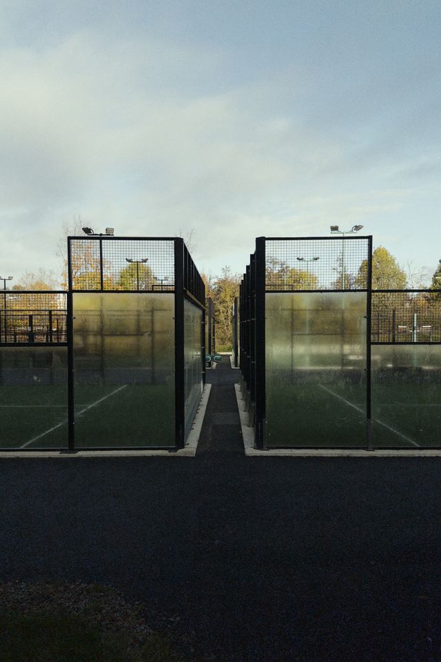 a photograph of a tennis court with a fenced in area with a tennis court