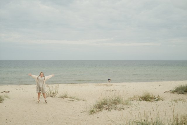 a photograph of a woman in a white dress standing on a beach
