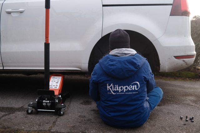 a photograph of a man sitting on the ground next to a car