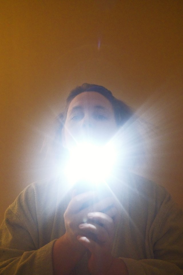 a photograph of a man holding a light up to his face