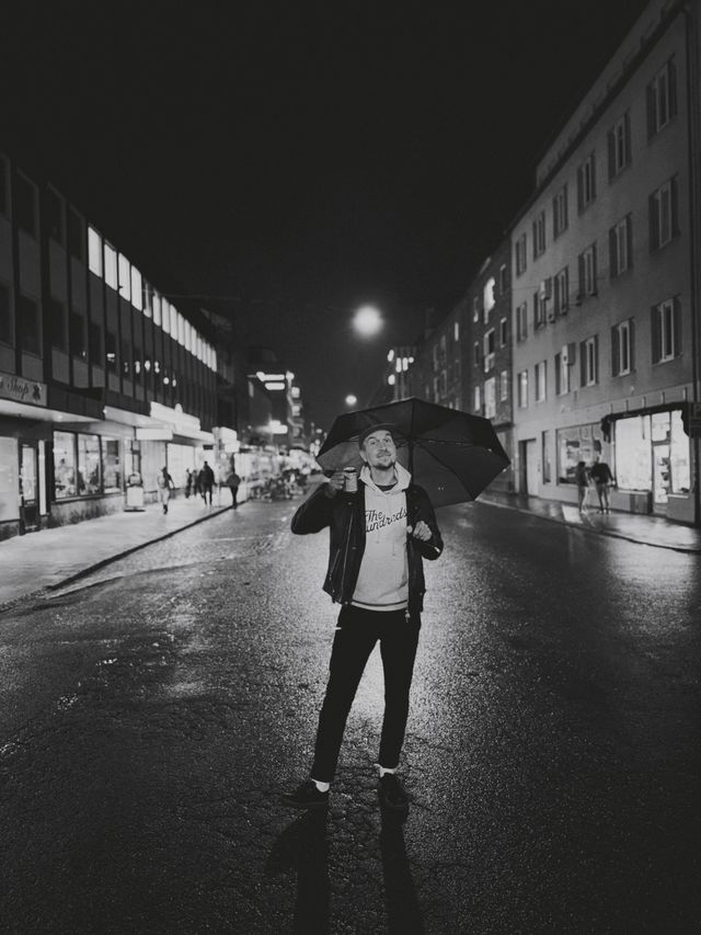 a photograph of a man holding an umbrella in the middle of a city street